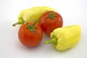 Peppers and tomatoes arranged on a white background - Two Hungarian wax peppers and tomatoes